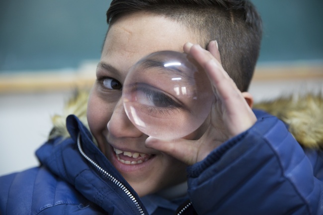 A child, uses big lens in order to improve his ability to see 